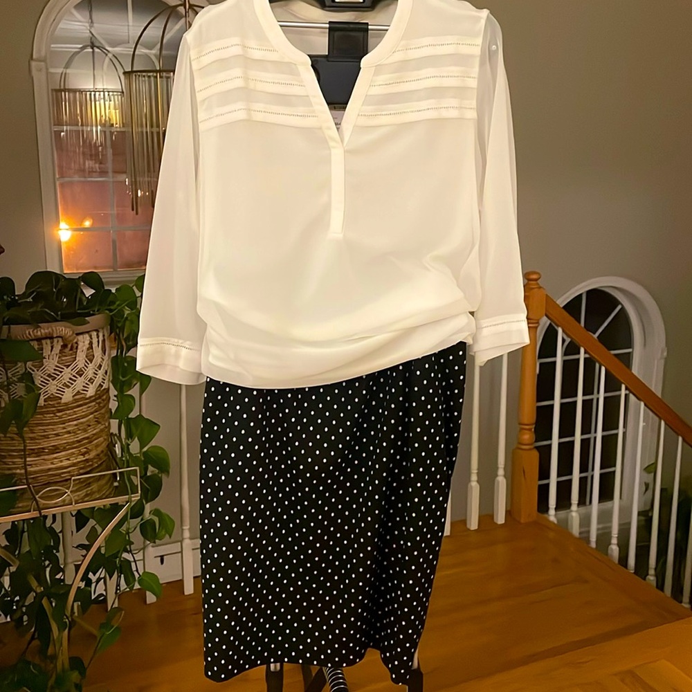 Black pencil skirt to the knee with white polkadots and back slit, size 18.